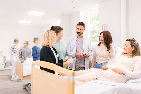 Zum Lernort - Skills Lab Schulungssituation mit Lehrkraft und Auszubildenden an einem Krankenbett